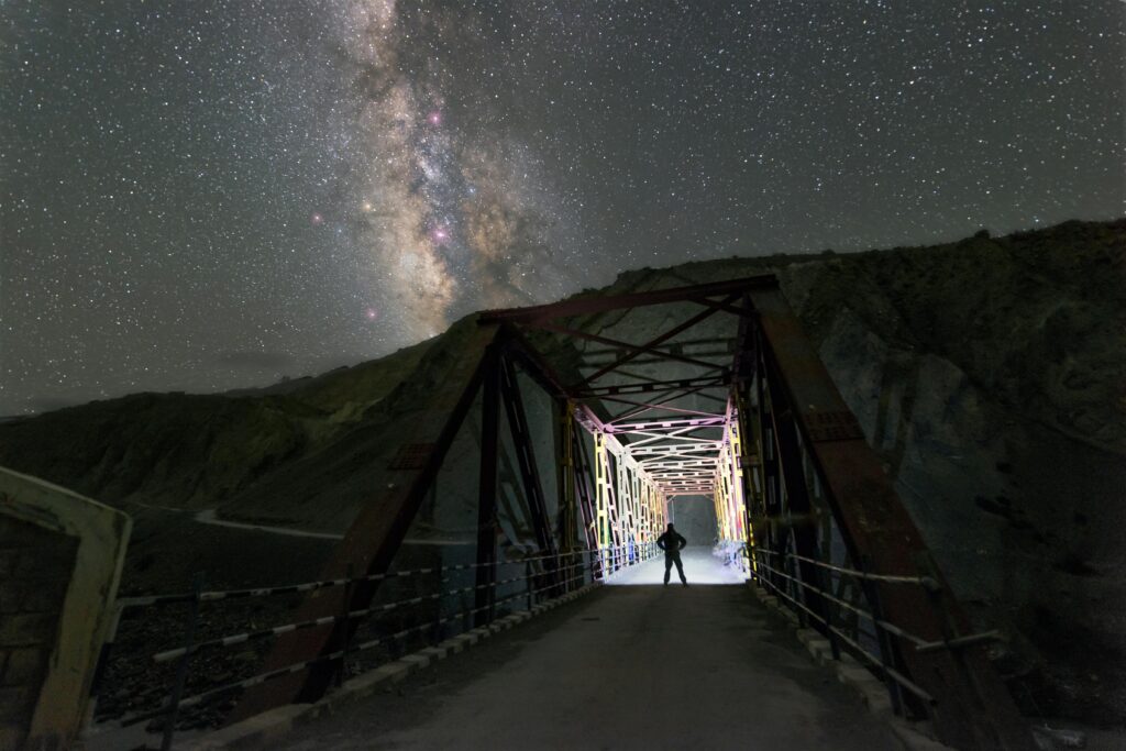 Silhouette on a bridge under the Milky Way in Kaza, India's night sky.
