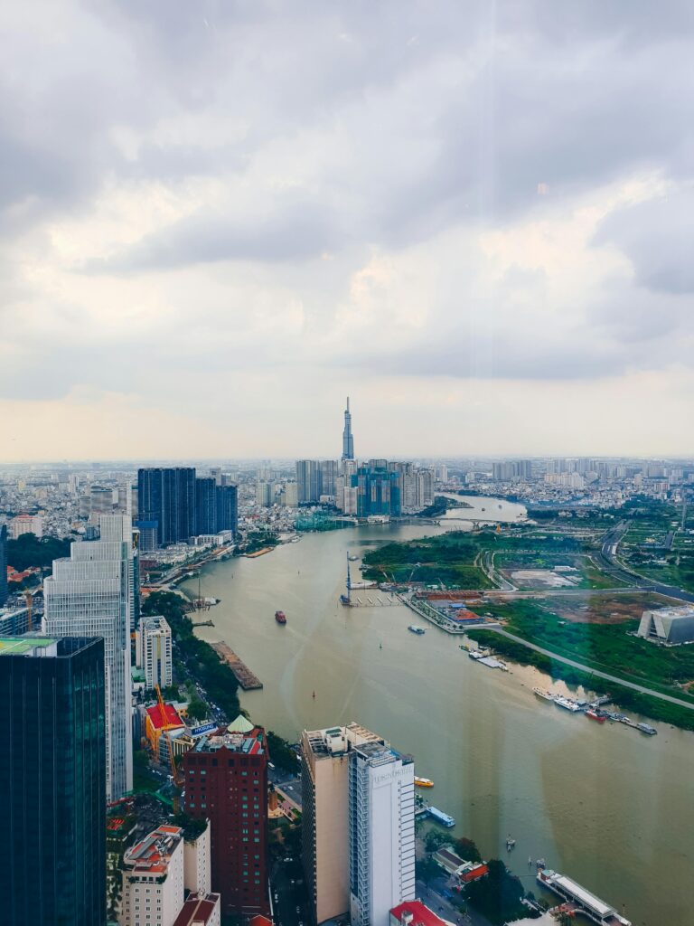 Captivating aerial image showcasing Saigon's vibrant skyline and river with modern skyscrapers and cloudy sky.