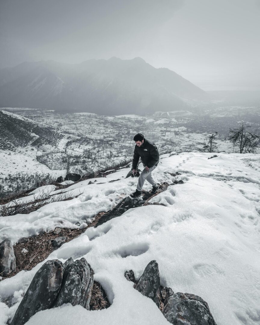 Single hiker climbing snowy mountain in Kashmir, showcasing winter adventure and scenic landscape.
