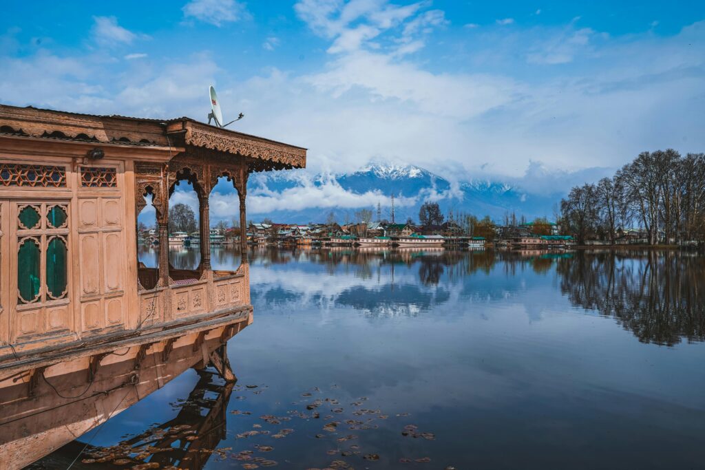 Houseboat over serene Dal Lake reflecting snow-capped mountains and traditional architecture.